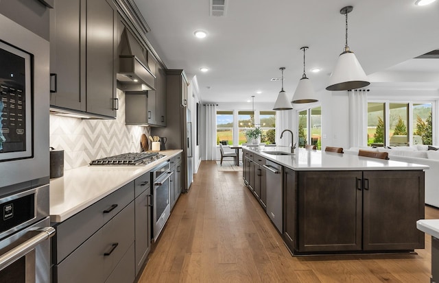 kitchen featuring open floor plan, appliances with stainless steel finishes, light countertops, and a sink