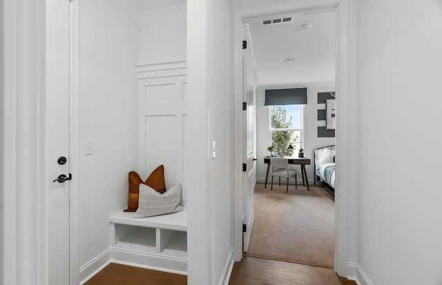 corridor featuring wood finished floors, carpet flooring, baseboards, and visible vents