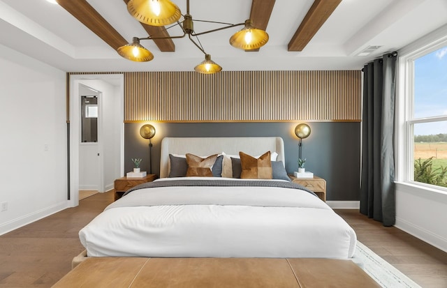 bedroom with beam ceiling, visible vents, baseboards, and wood finished floors