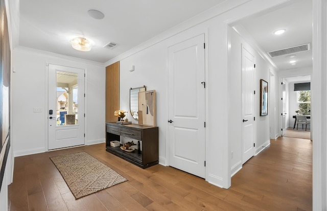 entrance foyer with crown molding, wood finished floors, and visible vents