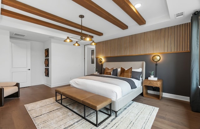 bedroom with visible vents, beam ceiling, baseboards, and wood finished floors