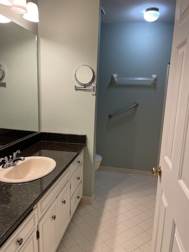 bathroom featuring tile patterned floors, baseboards, toilet, and vanity