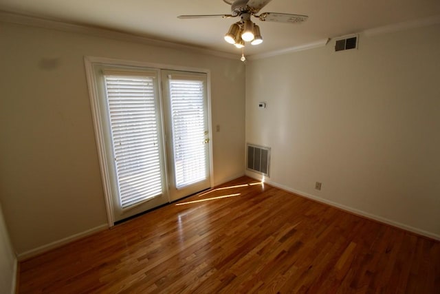 spare room featuring ceiling fan, visible vents, wood finished floors, and ornamental molding