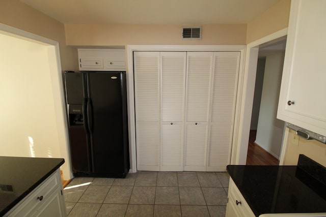 kitchen with visible vents, tile patterned flooring, black fridge with ice dispenser, white cabinetry, and dark countertops