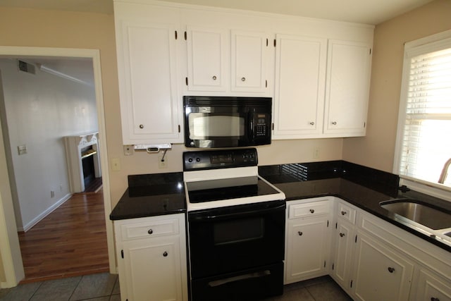 kitchen featuring visible vents, black microwave, electric range, white cabinetry, and a sink