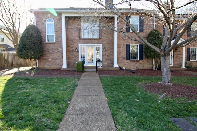 view of front of house featuring brick siding, a front yard, and fence