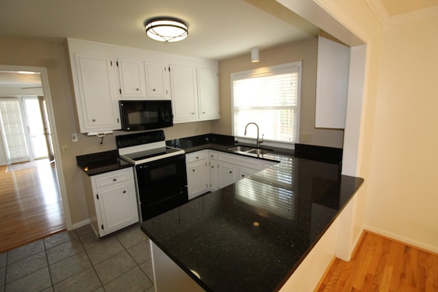 kitchen featuring black appliances, white cabinets, a peninsula, and a sink