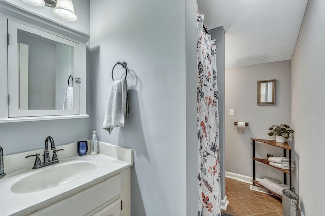 full bath with vanity, a shower with curtain, baseboards, a textured ceiling, and tile patterned floors