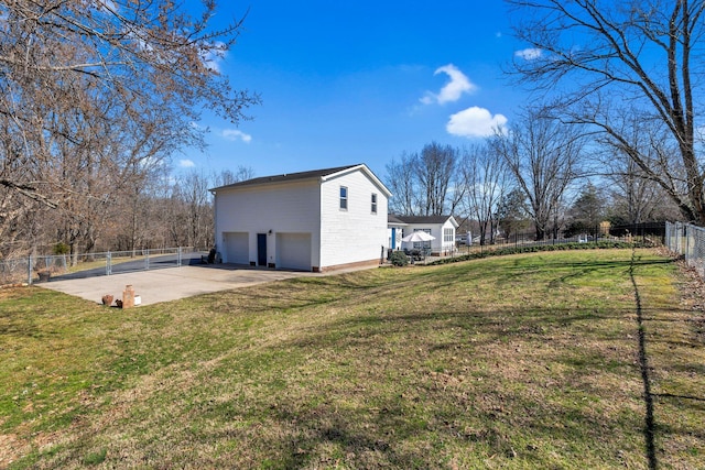 view of yard featuring an attached garage, concrete driveway, and fence