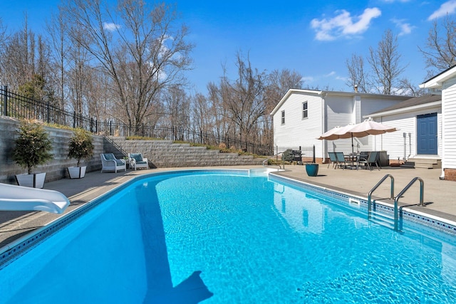 view of swimming pool featuring a fenced in pool, a water slide, a fenced backyard, entry steps, and a patio area