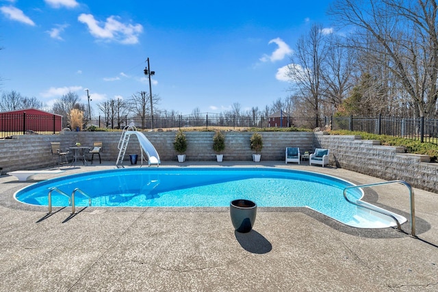 view of swimming pool featuring a patio, a fenced in pool, a water slide, a fenced backyard, and a diving board