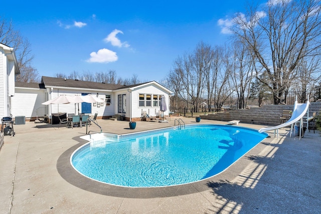 view of pool with a fenced in pool, a water slide, fence, cooling unit, and a patio area