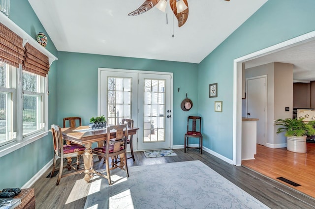 dining room with visible vents, lofted ceiling, a ceiling fan, wood finished floors, and baseboards