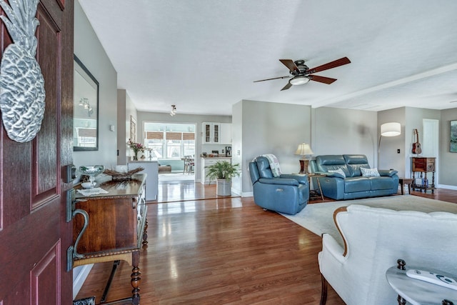 living room with baseboards, wood finished floors, and a ceiling fan