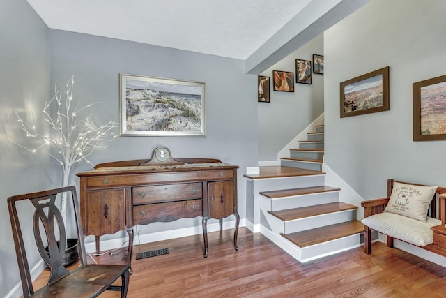 staircase featuring visible vents, baseboards, and wood finished floors