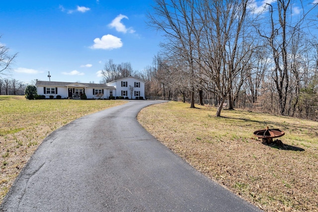 view of front of home with a front yard, driveway, and an outdoor fire pit