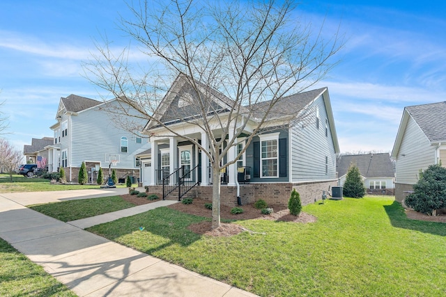 view of front of property featuring cooling unit, a porch, a front lawn, concrete driveway, and brick siding