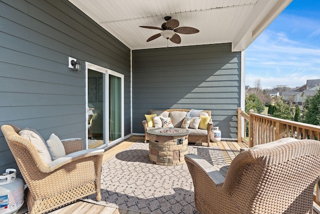 view of wooden balcony featuring a wooden deck, an outdoor living space with a fire pit, and a ceiling fan