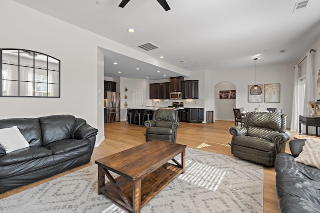 living area with light wood finished floors, visible vents, and ceiling fan