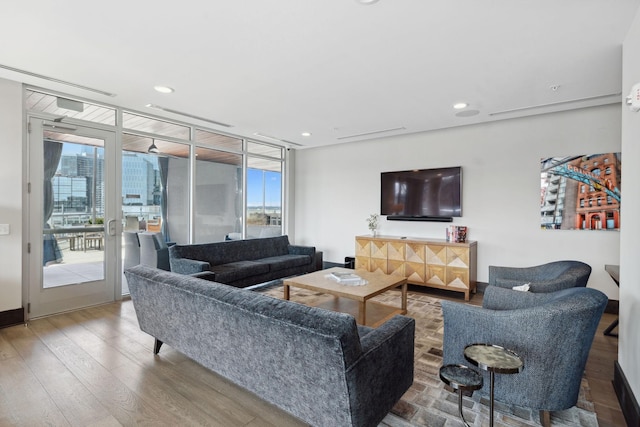 living area featuring a wealth of natural light, floor to ceiling windows, wood finished floors, and recessed lighting