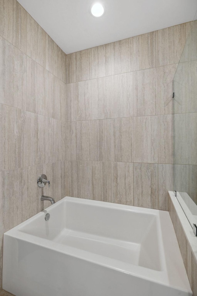 full bath featuring a bathing tub and tile walls