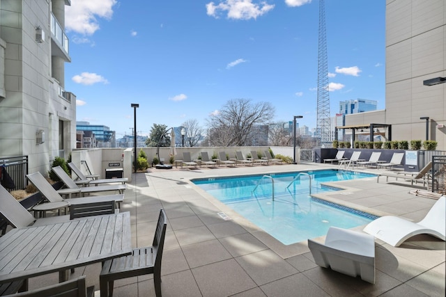 pool with a city view, a patio, and fence