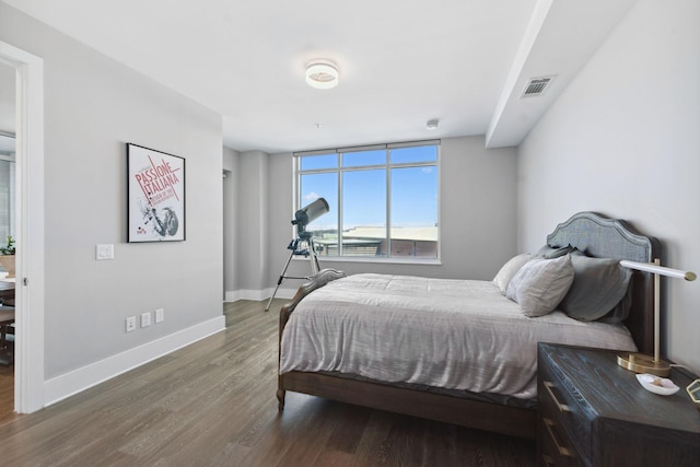 bedroom with visible vents, baseboards, and wood finished floors