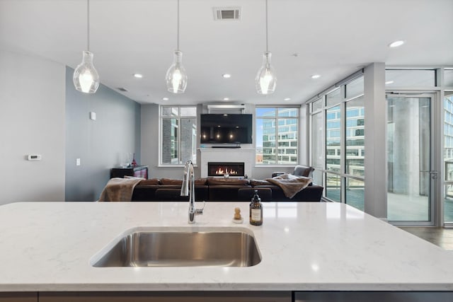 kitchen with visible vents, open floor plan, light stone countertops, and a sink