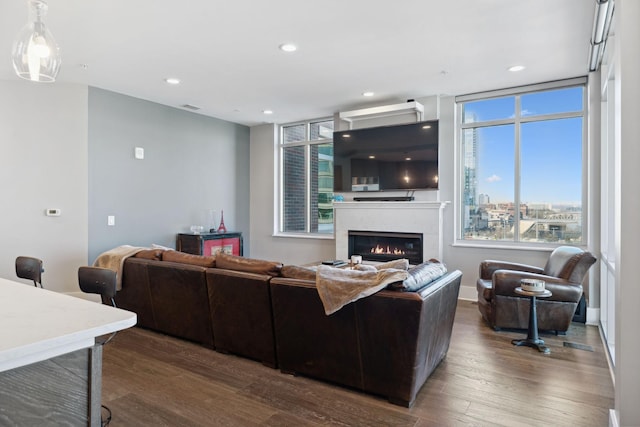 living area with a glass covered fireplace, visible vents, recessed lighting, and dark wood-style flooring