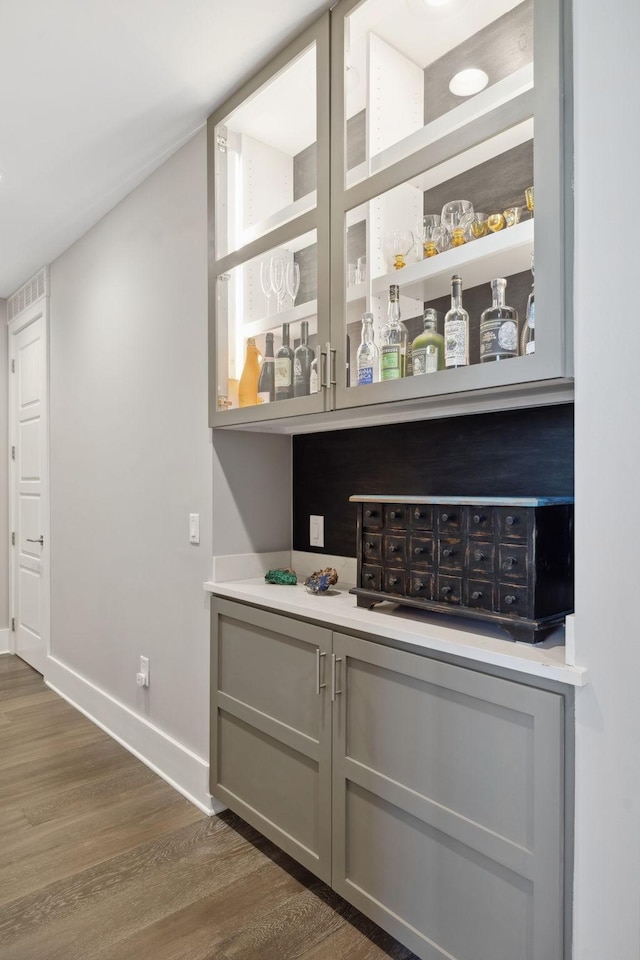 bar with baseboards, dark wood finished floors, and a dry bar