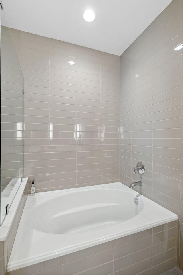 bathroom featuring tile walls and a relaxing tiled tub