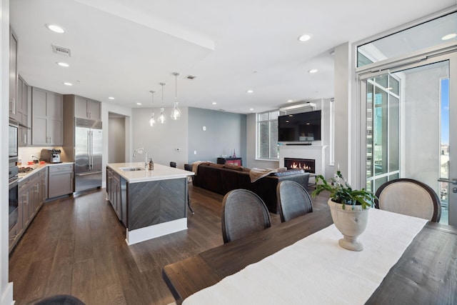 dining space with visible vents, dark wood finished floors, a lit fireplace, expansive windows, and recessed lighting