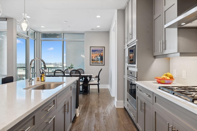 kitchen with a sink, backsplash, range hood, and gray cabinets