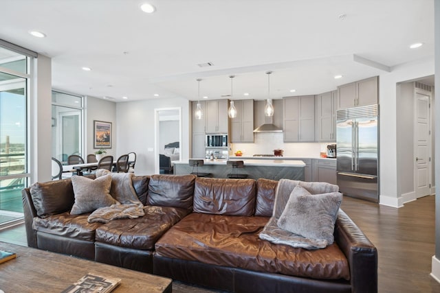 living room featuring dark wood finished floors, floor to ceiling windows, recessed lighting, and visible vents