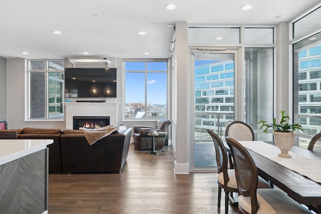 dining area featuring recessed lighting, expansive windows, a warm lit fireplace, and dark wood-style flooring