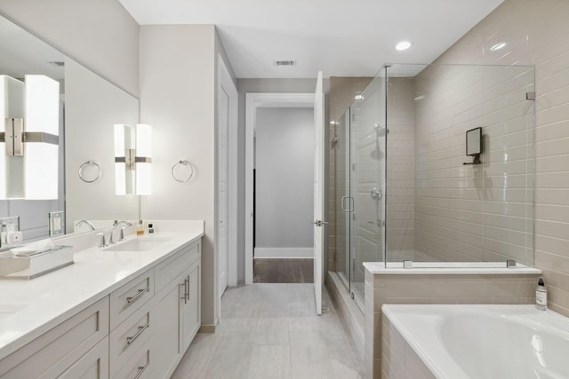 full bath featuring visible vents, double vanity, a stall shower, a sink, and a relaxing tiled tub