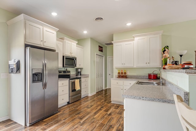 kitchen with a sink, stainless steel appliances, visible vents, and dark wood-style floors