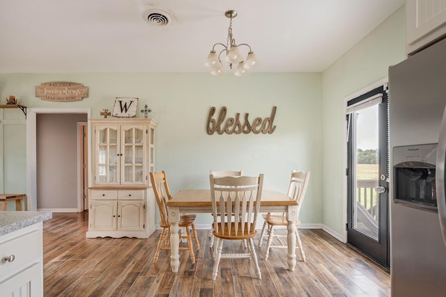 dining room featuring an inviting chandelier, wood finished floors, visible vents, and baseboards