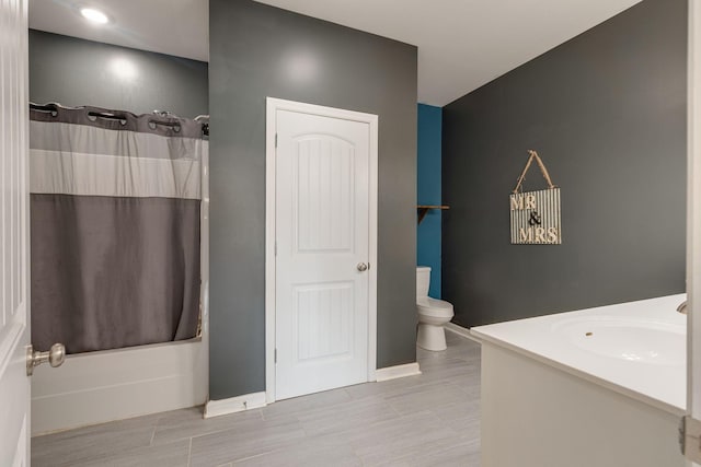 full bath featuring toilet, shower / bath combo, baseboards, and a sink