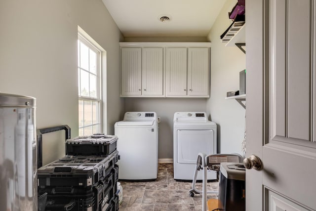 washroom with stone finish flooring, visible vents, cabinet space, and washing machine and clothes dryer