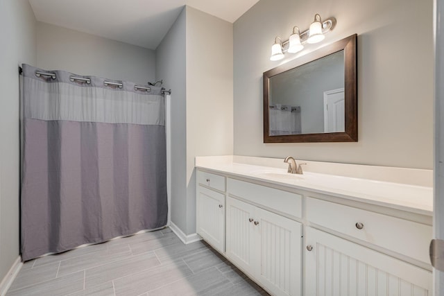 full bath with vanity, a shower with curtain, and baseboards