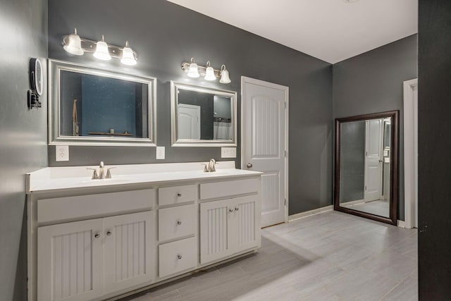 full bathroom with a sink, baseboards, and double vanity