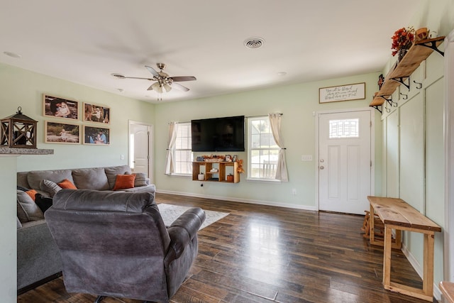 living area featuring visible vents, a ceiling fan, baseboards, and dark wood-style flooring