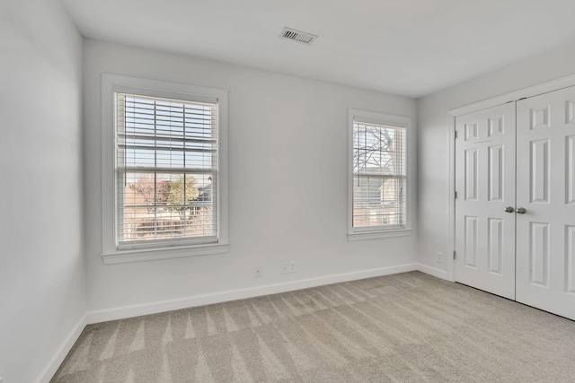 unfurnished bedroom with a closet, baseboards, visible vents, and carpet floors