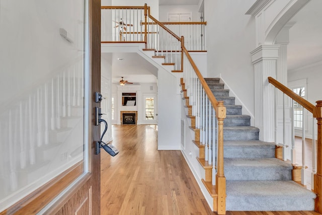 foyer featuring light wood-style flooring, arched walkways, a high ceiling, ceiling fan, and stairs