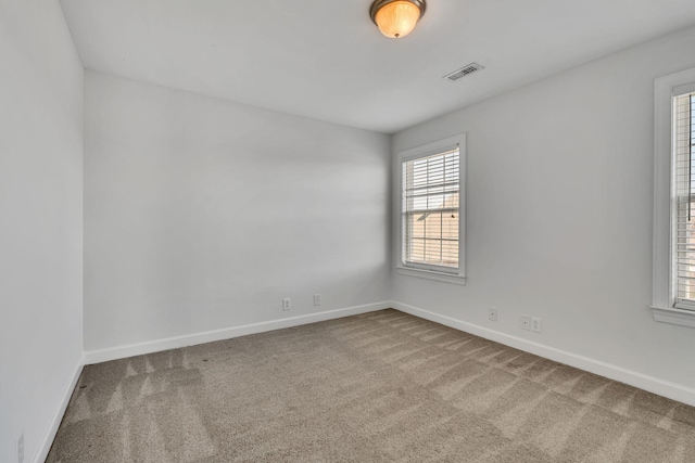 carpeted spare room featuring visible vents and baseboards