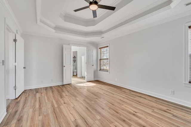 unfurnished bedroom with light wood-type flooring, visible vents, ornamental molding, a tray ceiling, and baseboards