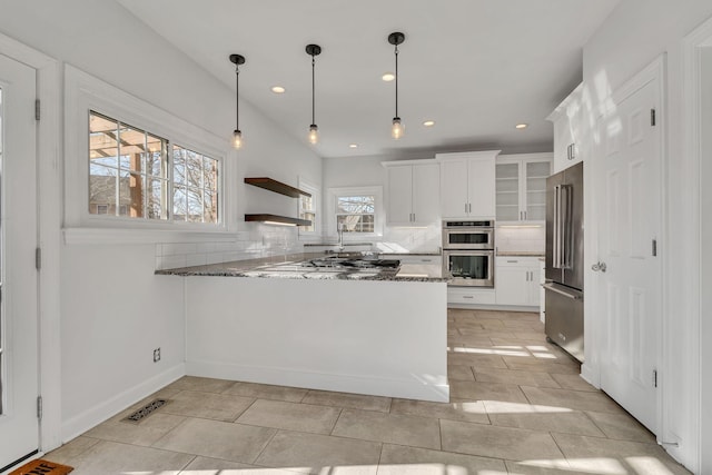 kitchen featuring visible vents, stone countertops, tasteful backsplash, stainless steel appliances, and a peninsula