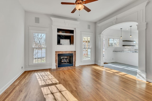 unfurnished living room featuring visible vents, baseboards, a tiled fireplace, wood finished floors, and a ceiling fan