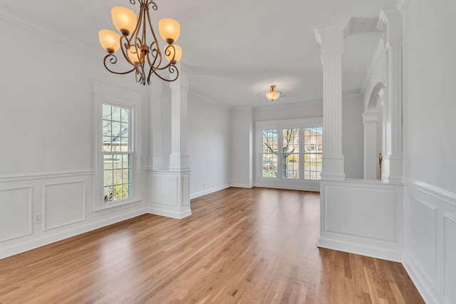 interior space featuring a wealth of natural light, light wood finished floors, crown molding, and decorative columns